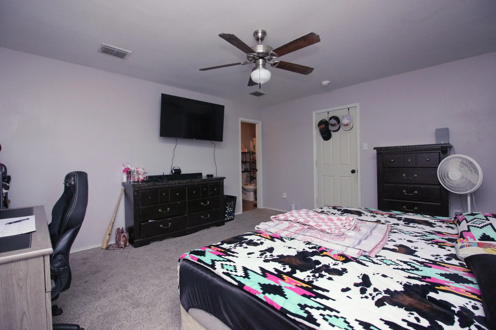 Ceiling fan with light fixture, wall-mounted television, and a white interior door
