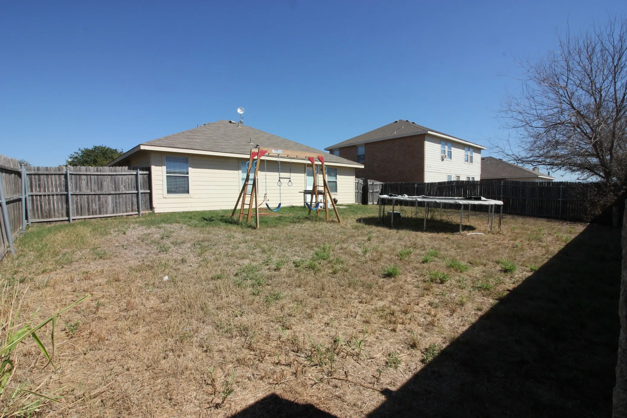 Expansive backyard featuring a full perimeter privacy fence and a one-story dwelling with siding and a shingle roof
