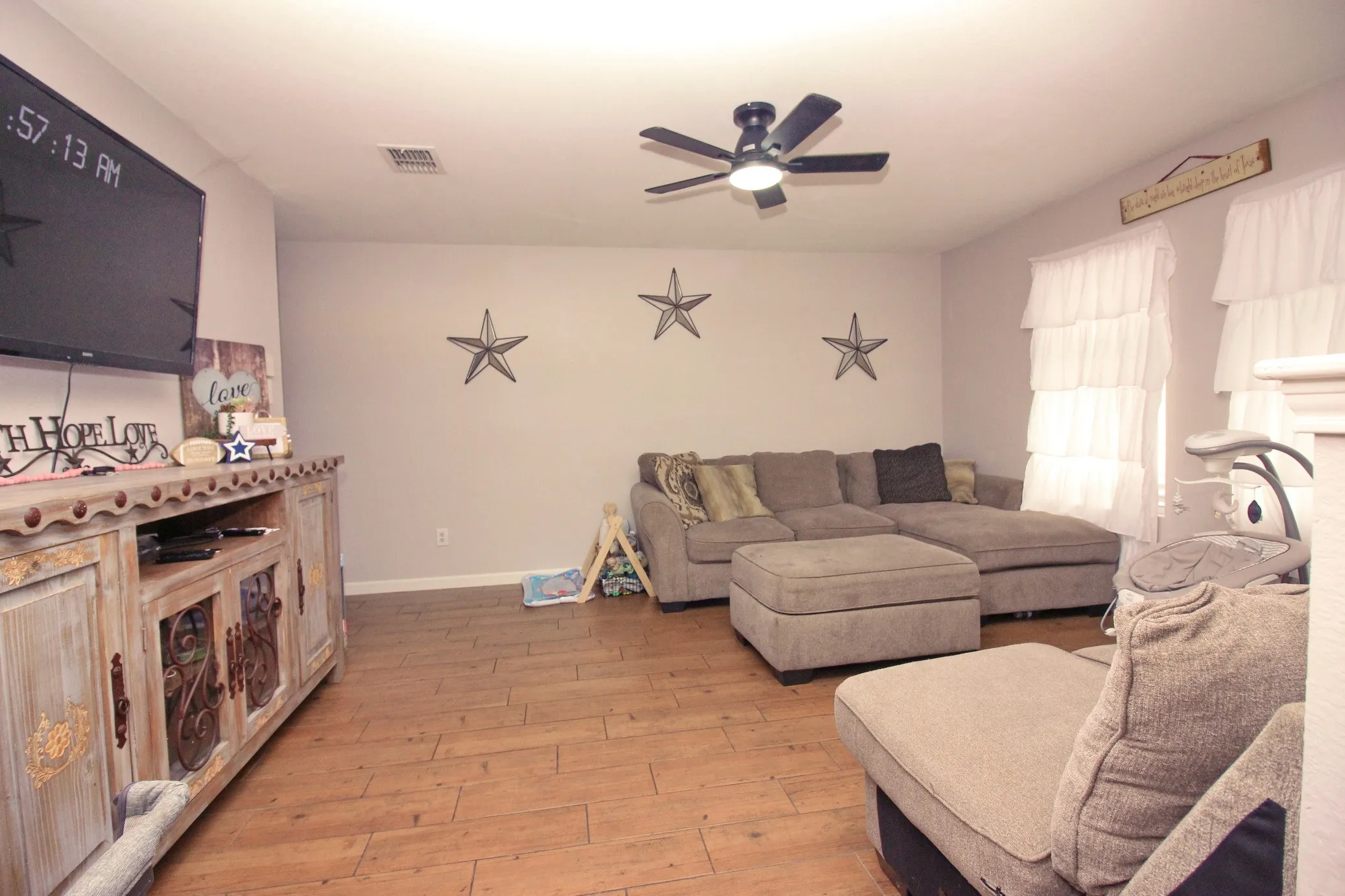Wood-finish flooring, ceiling fan with integrated lighting, and multiple windows