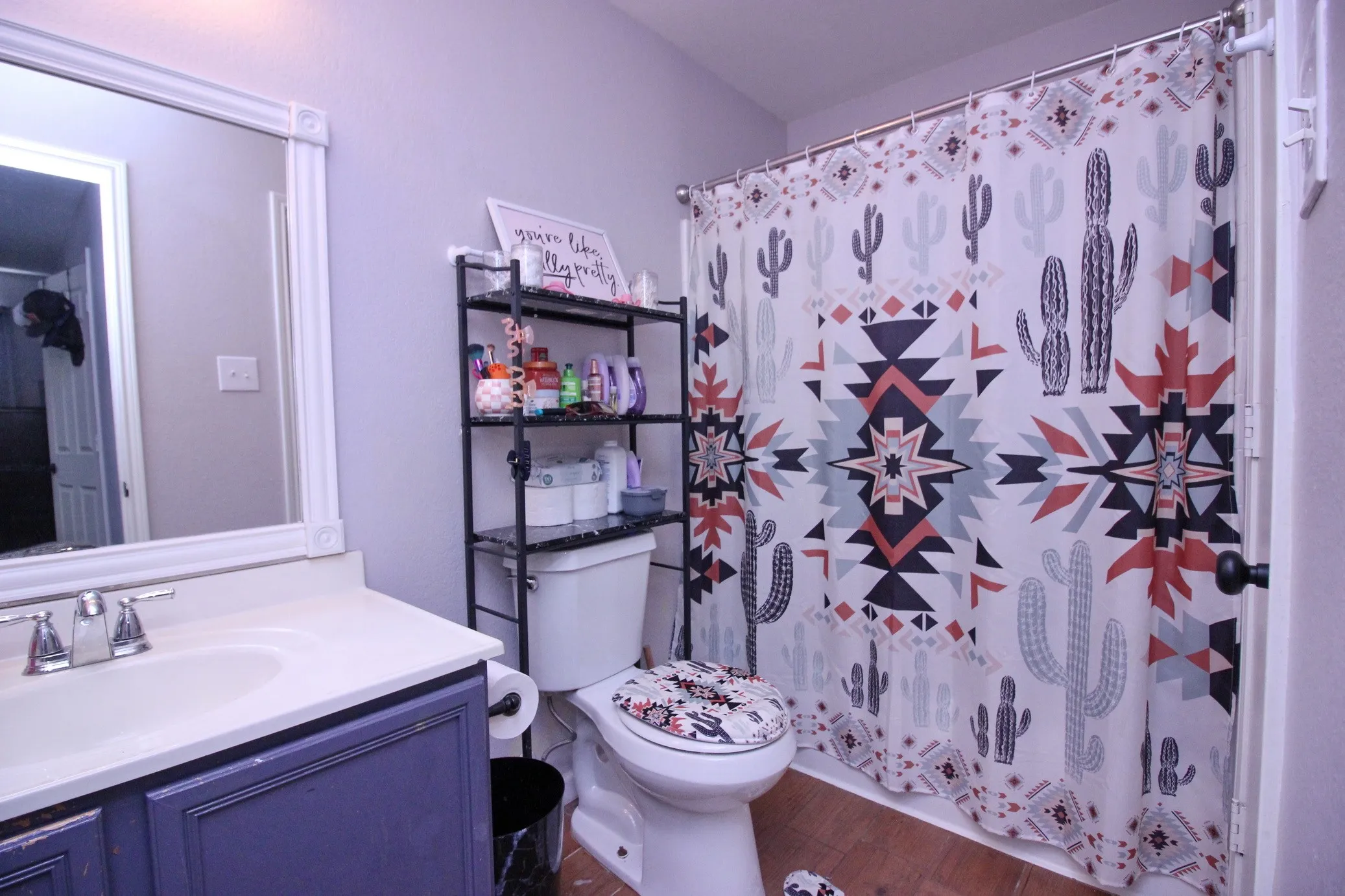 Bathroom featuring a vanity with a single sink, an integrated countertop, and a framed mirror
