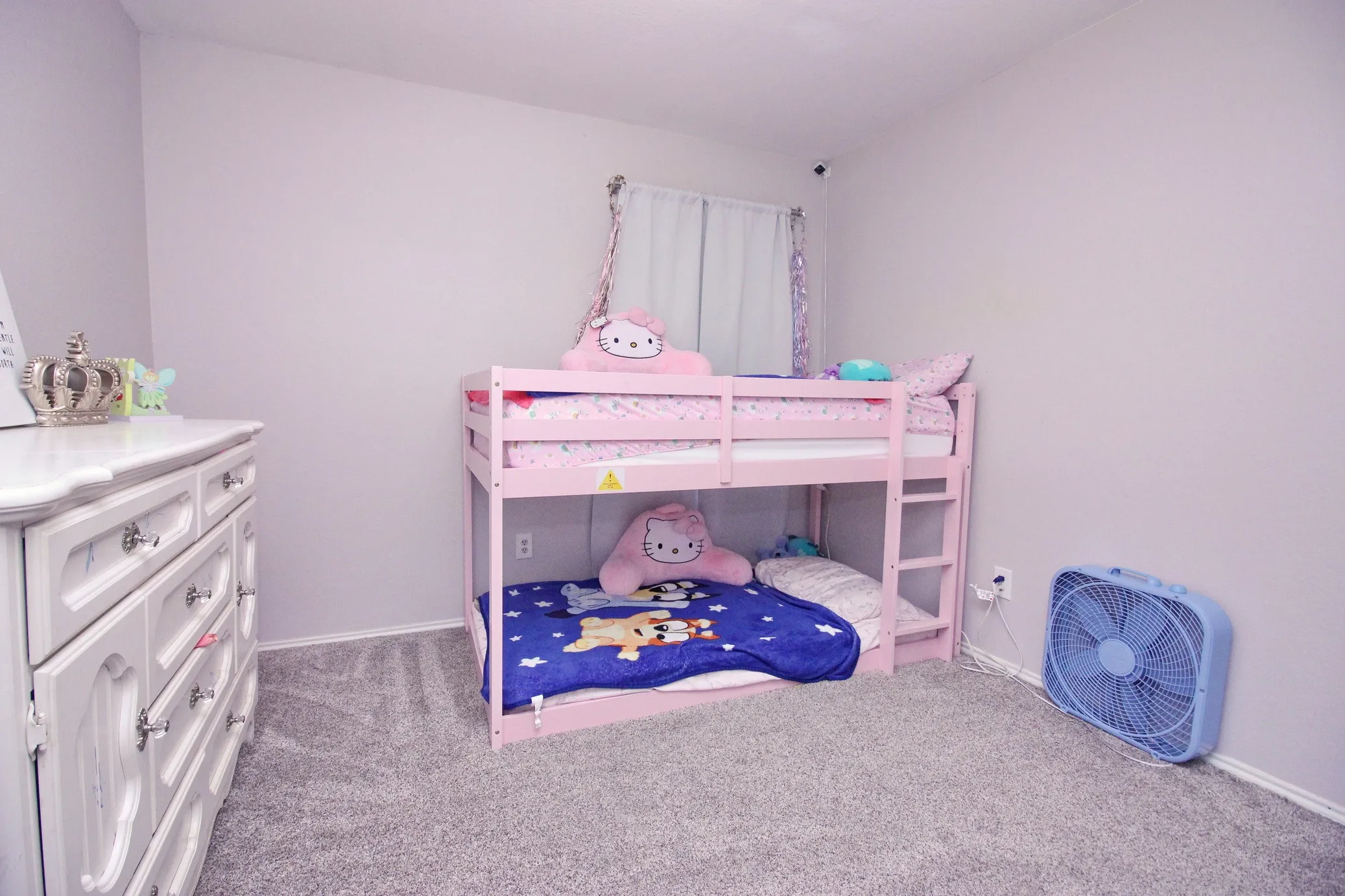 Gray-toned carpeting, light-colored walls, and a window with curtains