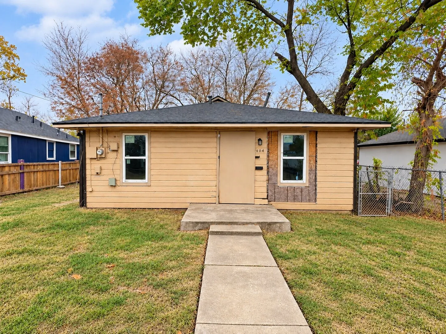 Single-story exterior with horizontal siding, a gabled roof, and a concrete pathway leading to the front entry