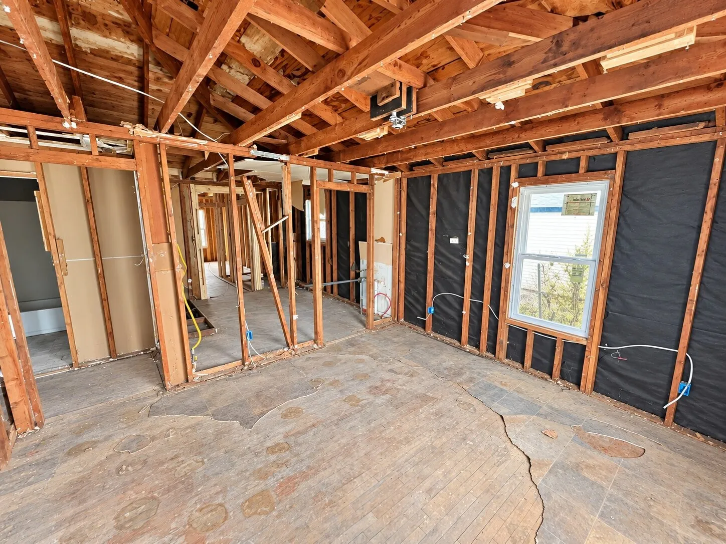 Exposed wood framing, visible ceiling joists, and floorboards with exposed subfloor