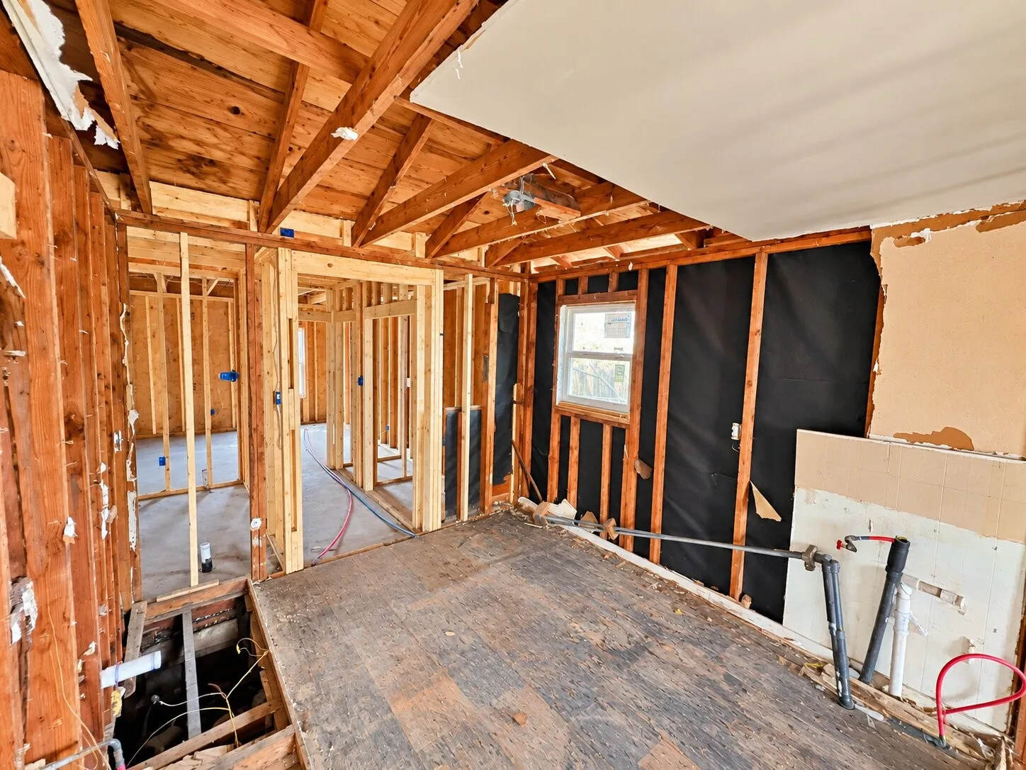 Exposed wood framing, visible ceiling joists, and a single-pane window