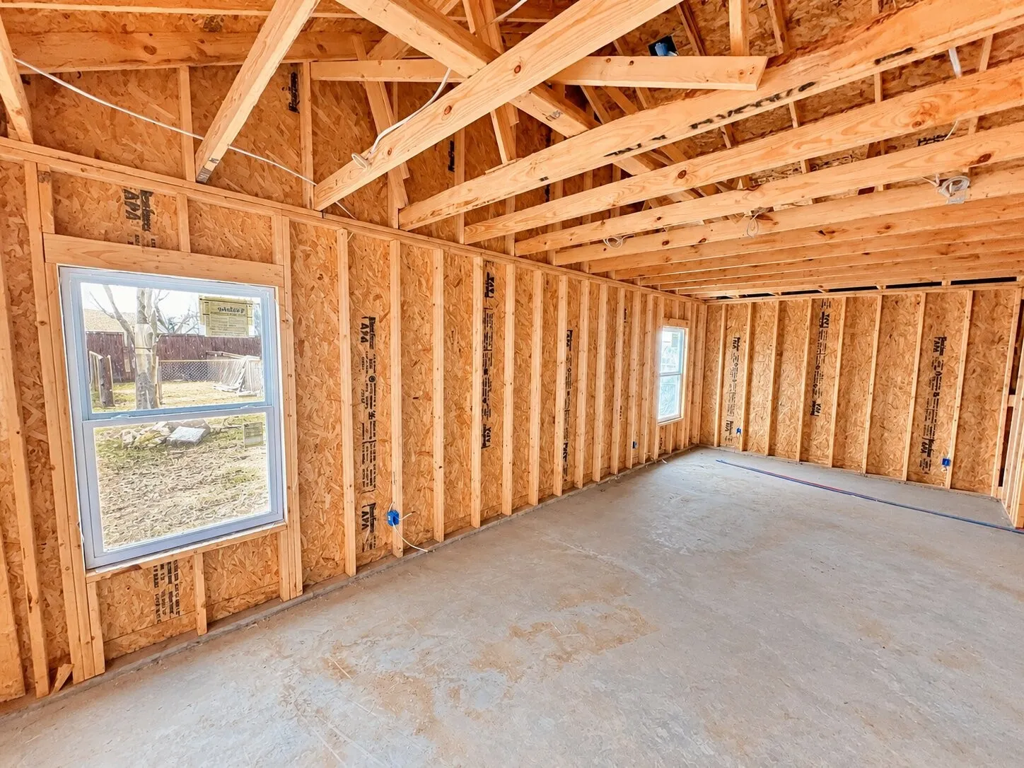 Exposed wood framing, durable concrete flooring, and multiple windows