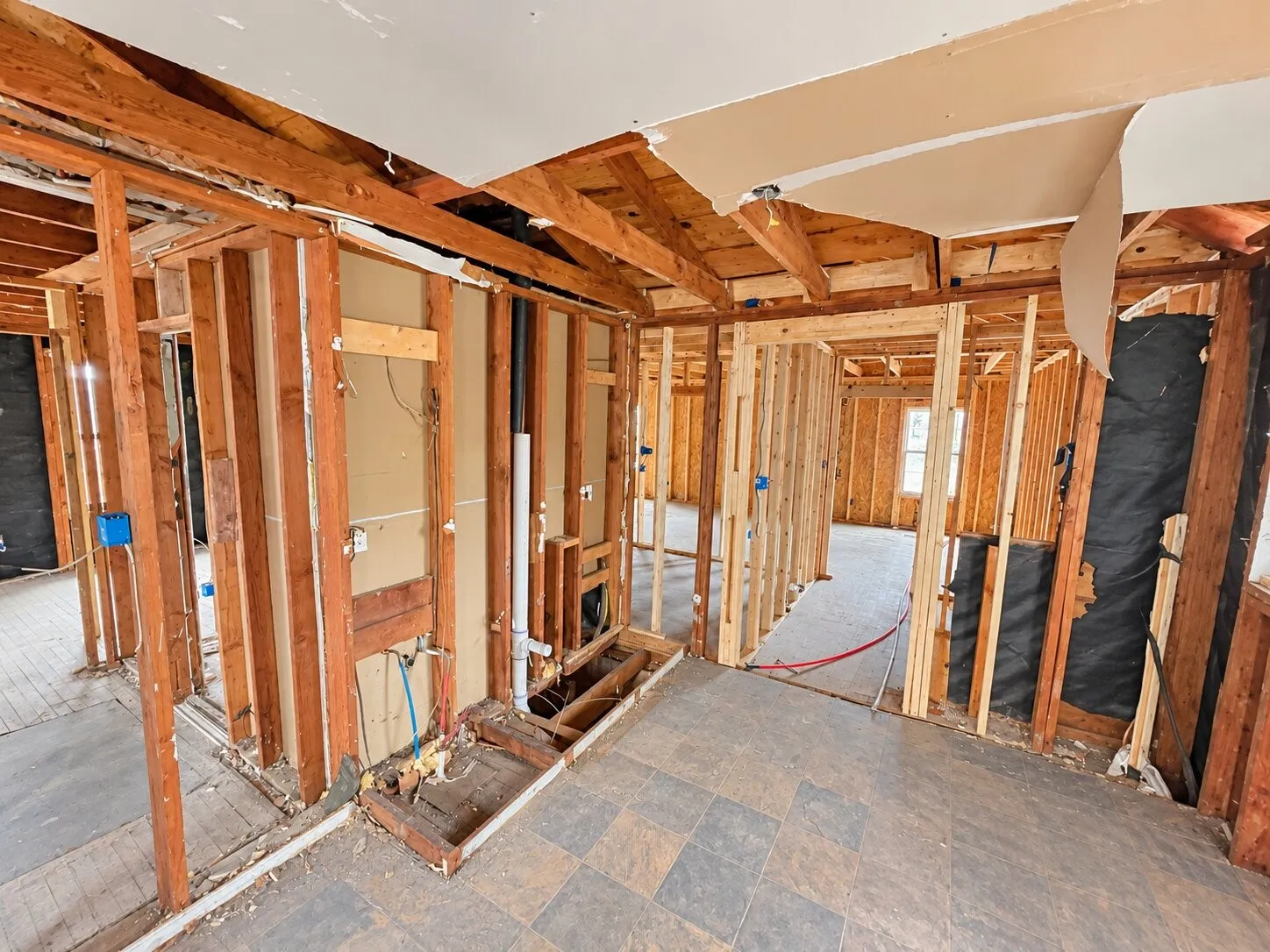 Exposed wooden framing, visible plumbing, and electrical rough-in