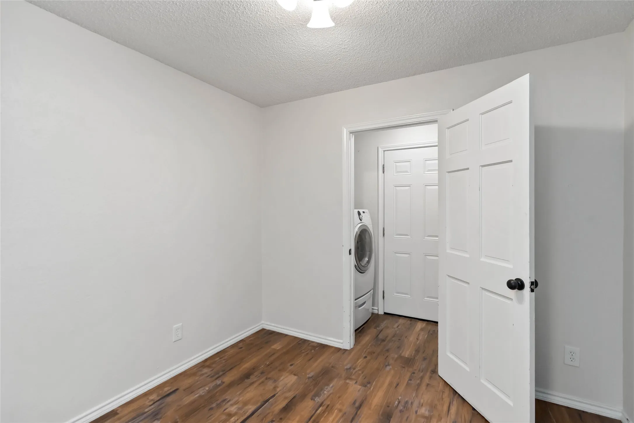 Interior room featuring wood-finish flooring, white baseboards, and light neutral wall paint