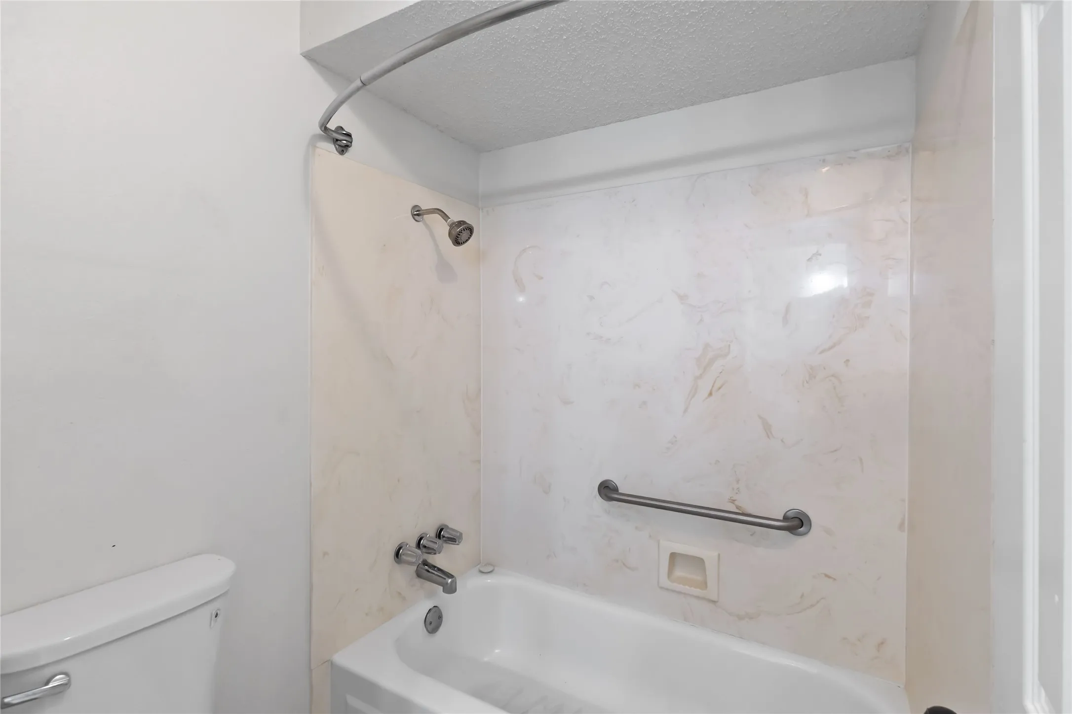 Full bathtub with chrome fixtures, a curved shower rod, and a shower head