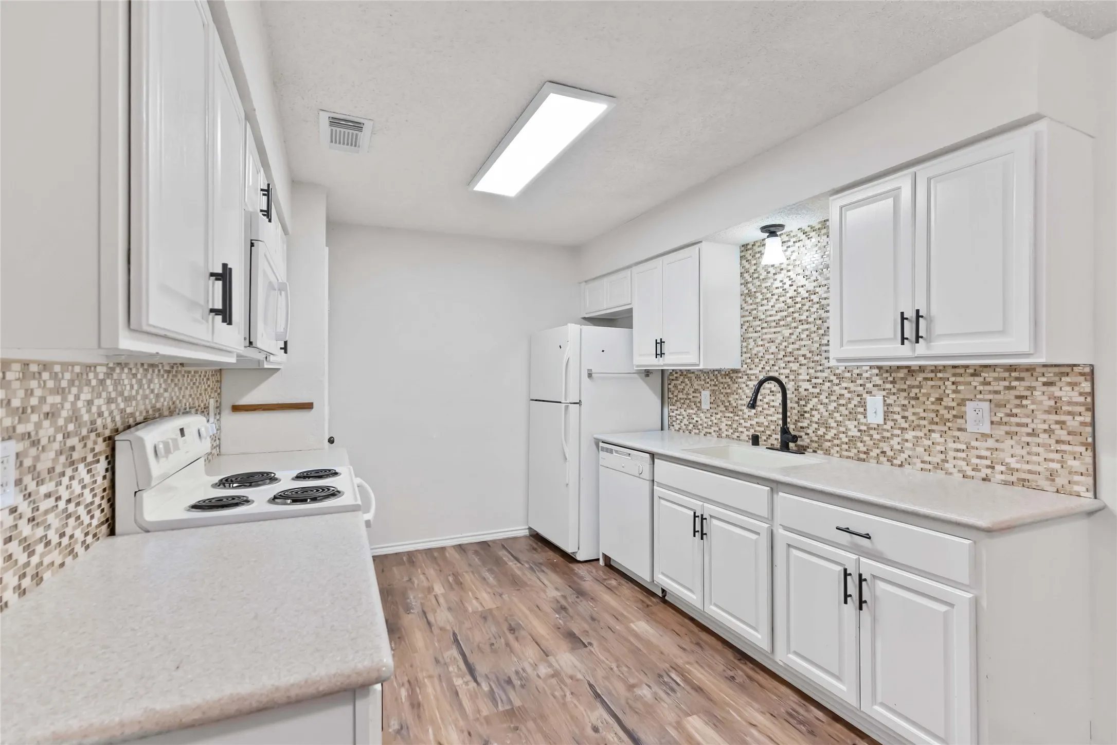 Kitchen featuring white cabinetry, light countertops, mosaic tile backsplash, wood-finish flooring, and white appliances