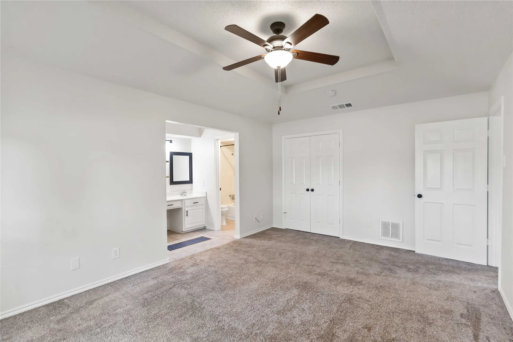 Spacious bedroom featuring plush gray carpeting and white walls