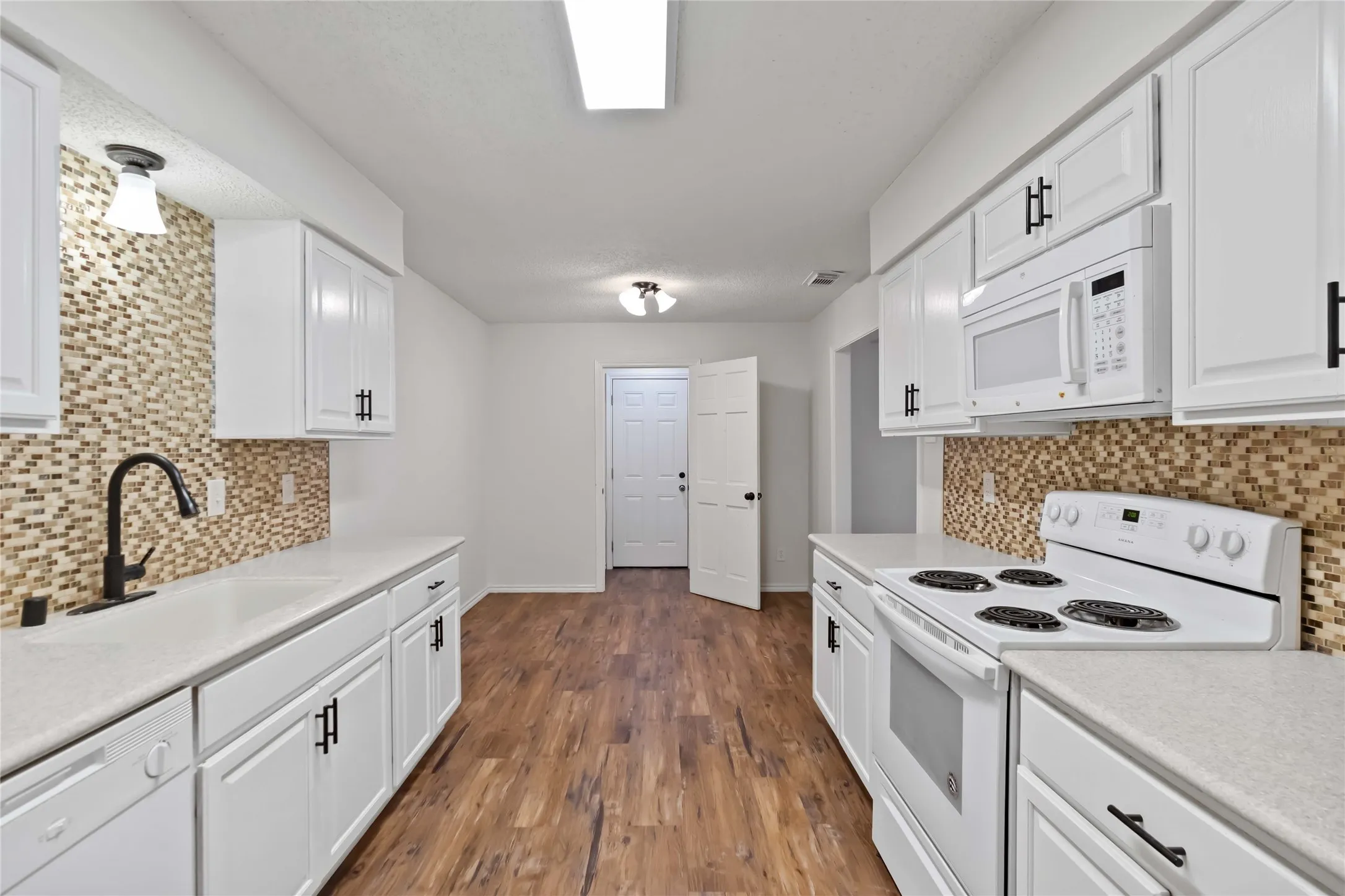 Kitchen featuring white cabinetry, light countertops, wood-finish flooring, and a mosaic tile backsplash