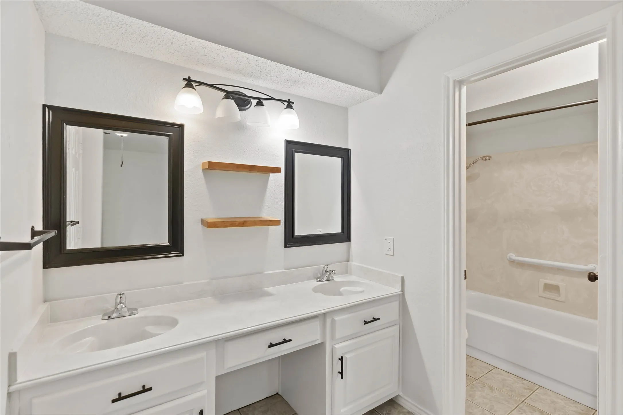 Dual vanity with white cabinetry, integrated sinks, and individual framed mirrors