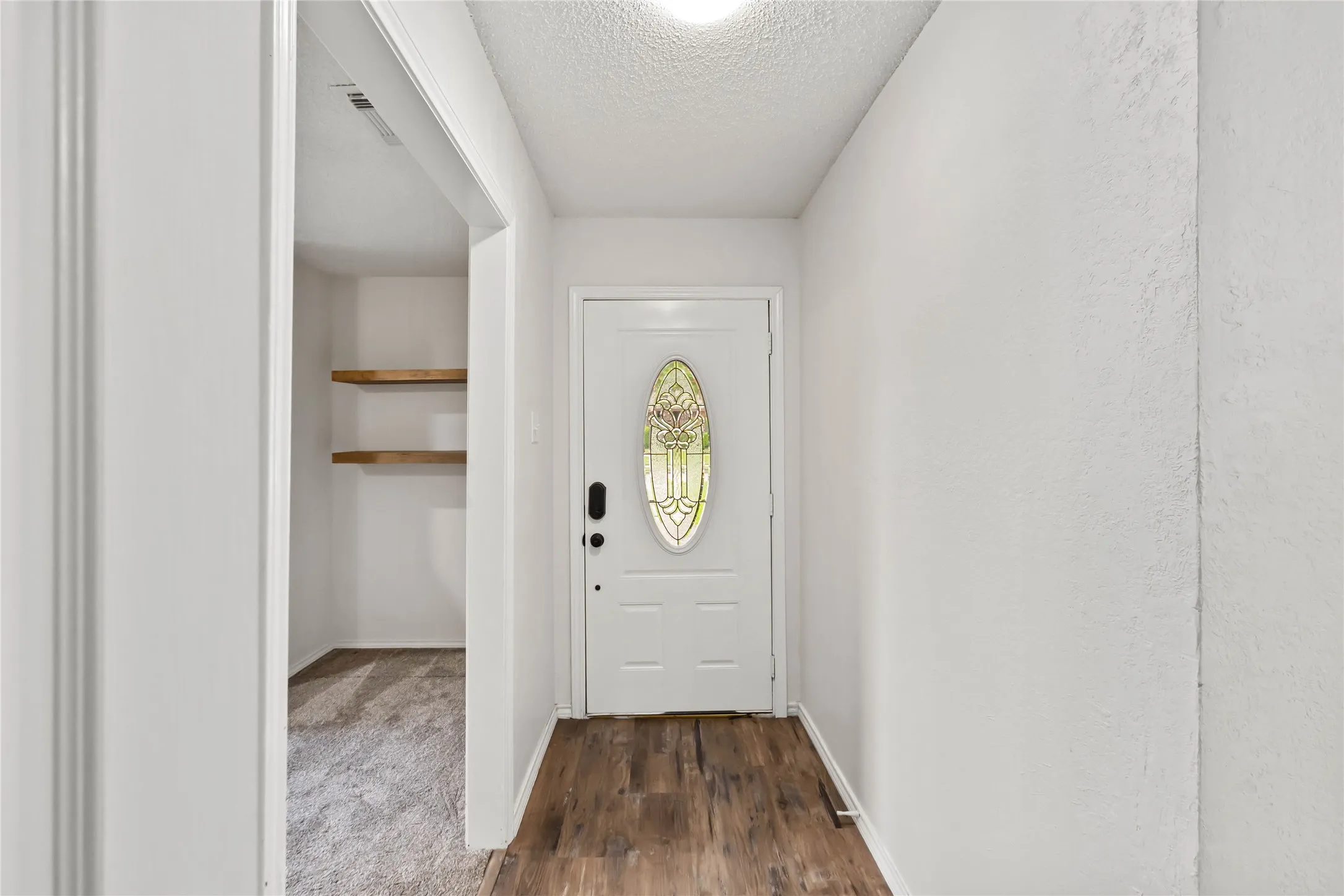 Entryway featuring wood-finish flooring, a white door with decorative glass insert, and neutral wall tones