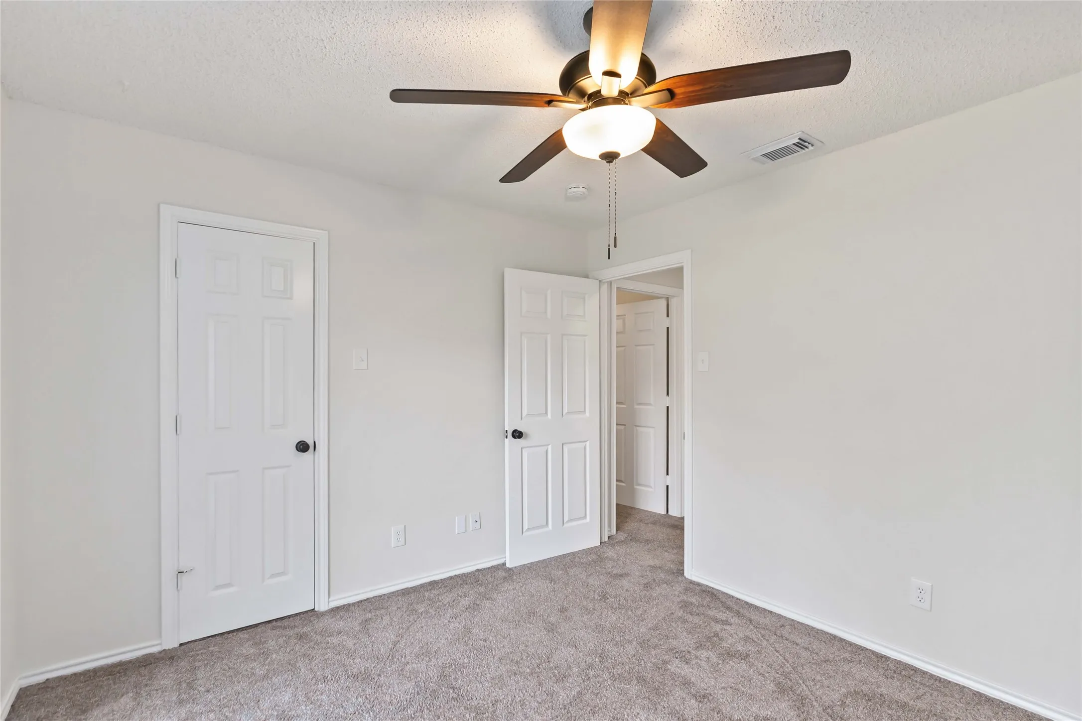 Neutral-toned interior room featuring light gray carpeting and white walls