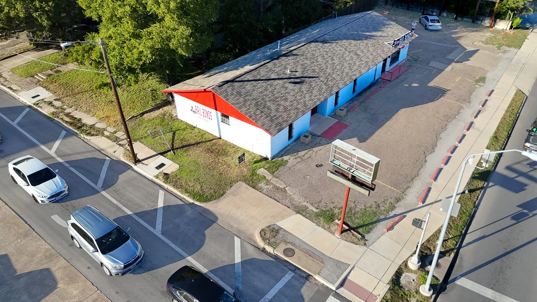 Single-story building with a shingle roof, extensive paved lot, and prominent street signage