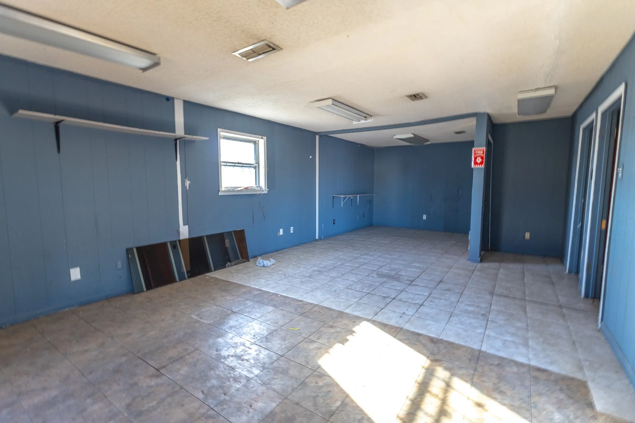 Spacious interior with tile flooring, wall-mounted shelving, and multiple entryways