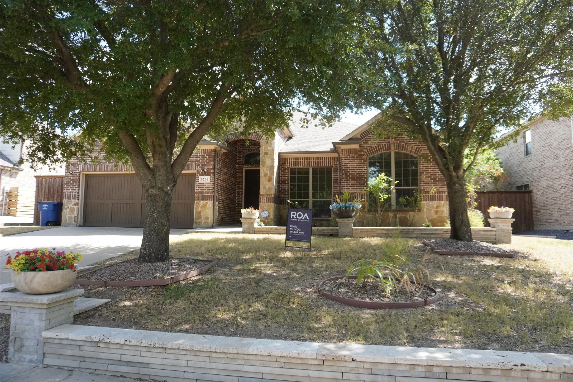 Brick and stone facade residence with an arched entryway, arched window, and attached garage