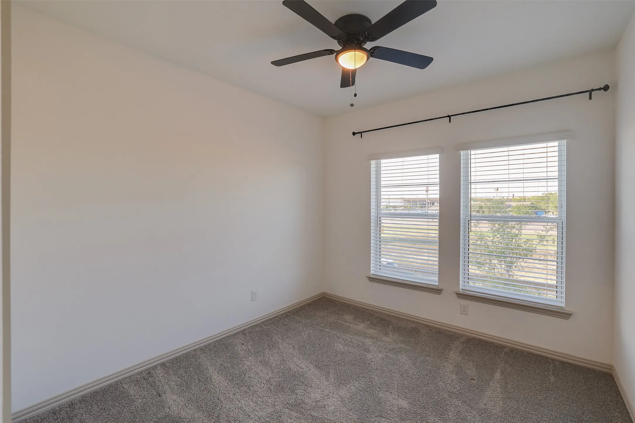 Plush carpet flooring, dual windows, and a ceiling fan with integrated lighting