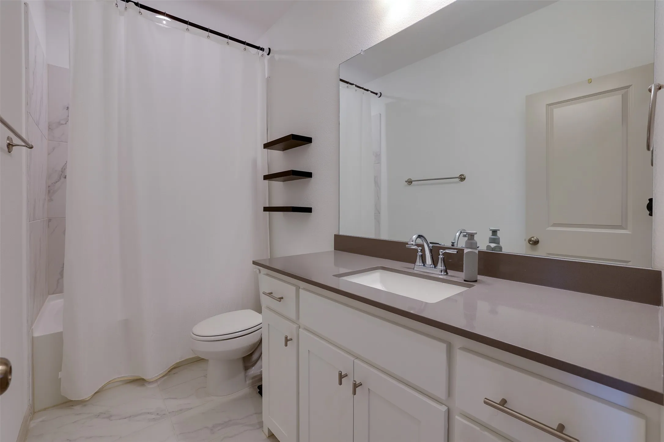 White vanity with shaker-style cabinetry, a built-in rectangular sink, and a solid surface countertop