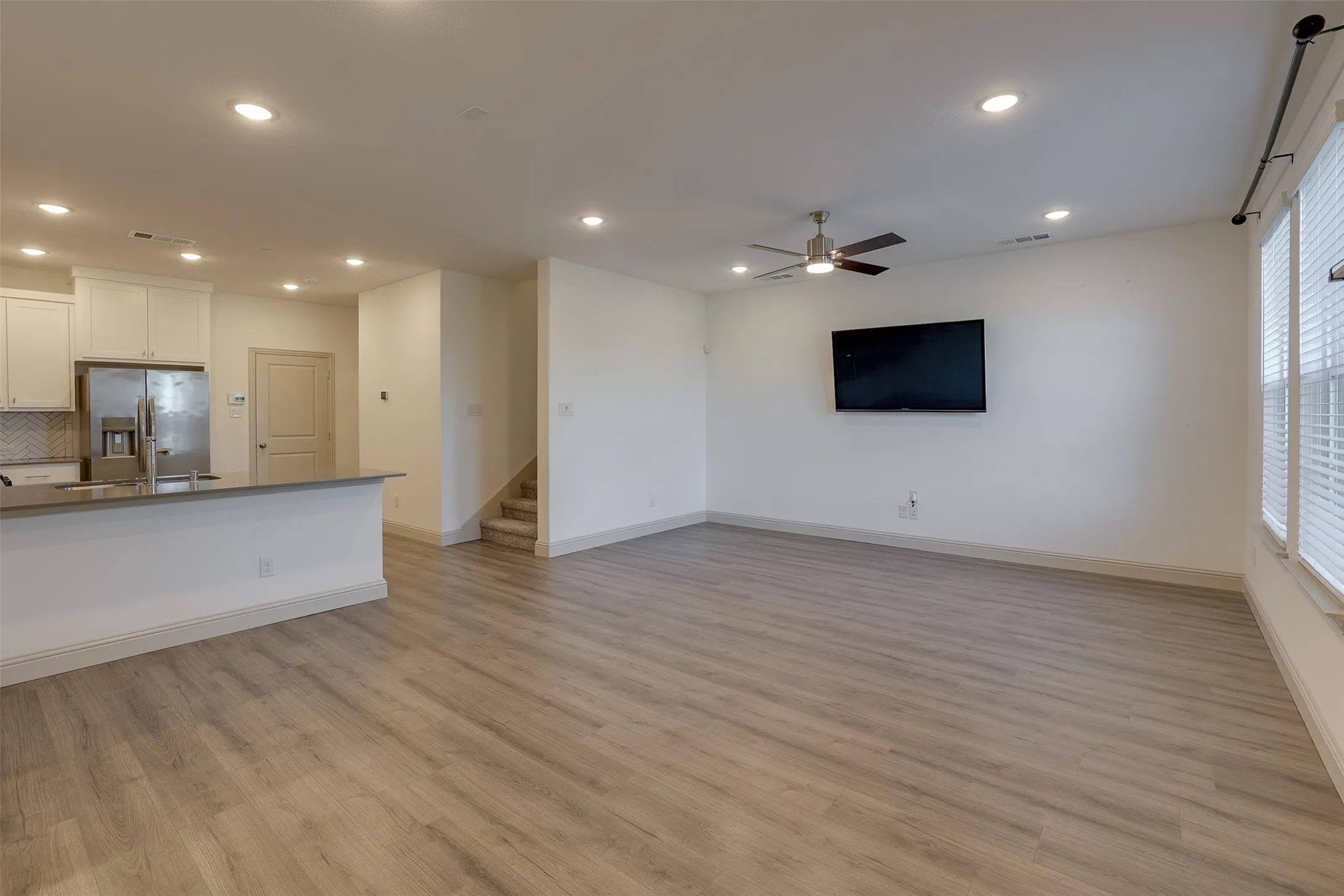 Open-concept living area featuring wood-finish flooring, recessed lighting, and a ceiling fan