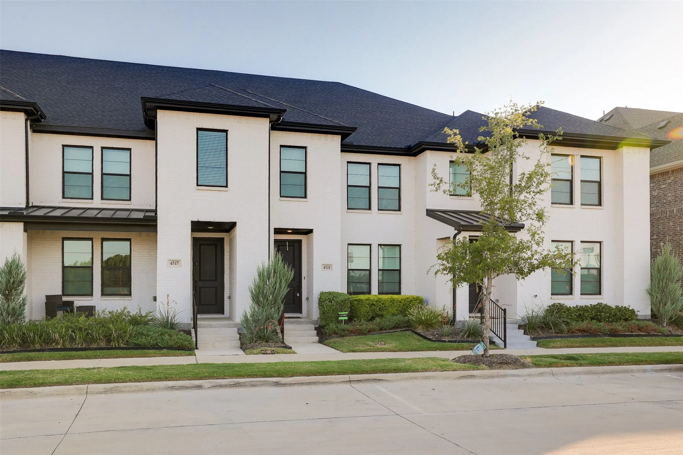 Contemporary facade with a dark shingle roof and contrasting white brick exterior