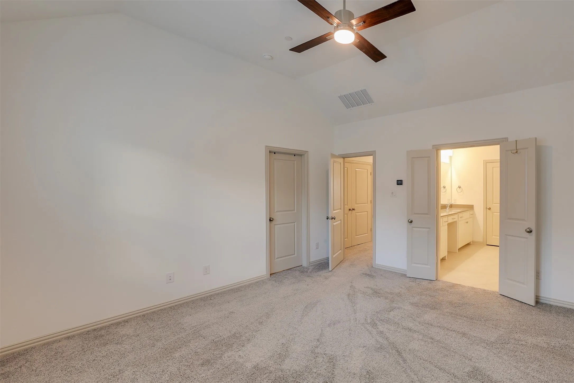 Vaulted ceiling with a ceiling fan, carpet flooring, recessed lighting, and panel doors