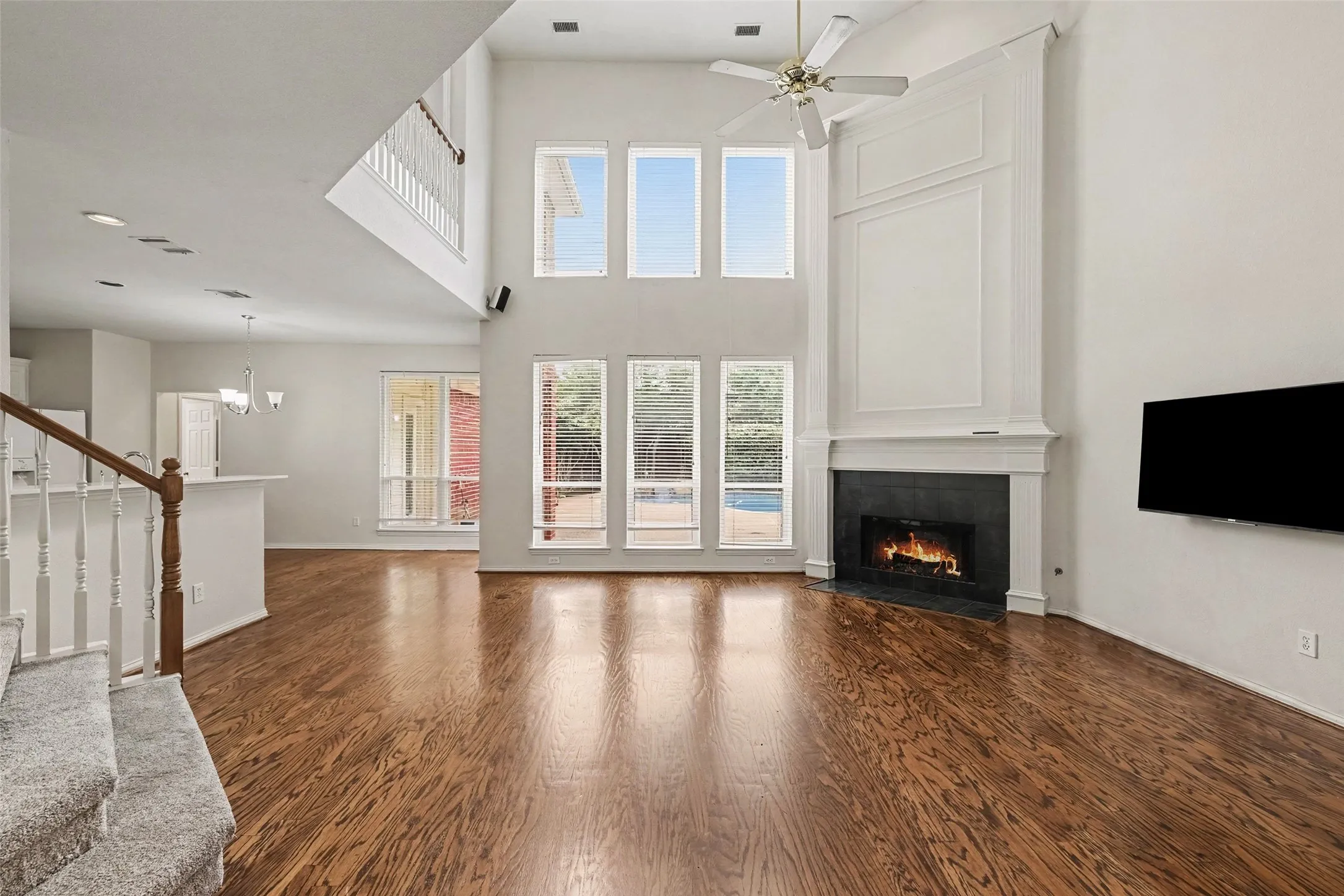 Soaring two-story great room with cathedral ceiling and ceiling fan, anchored by a gas fireplace with surround