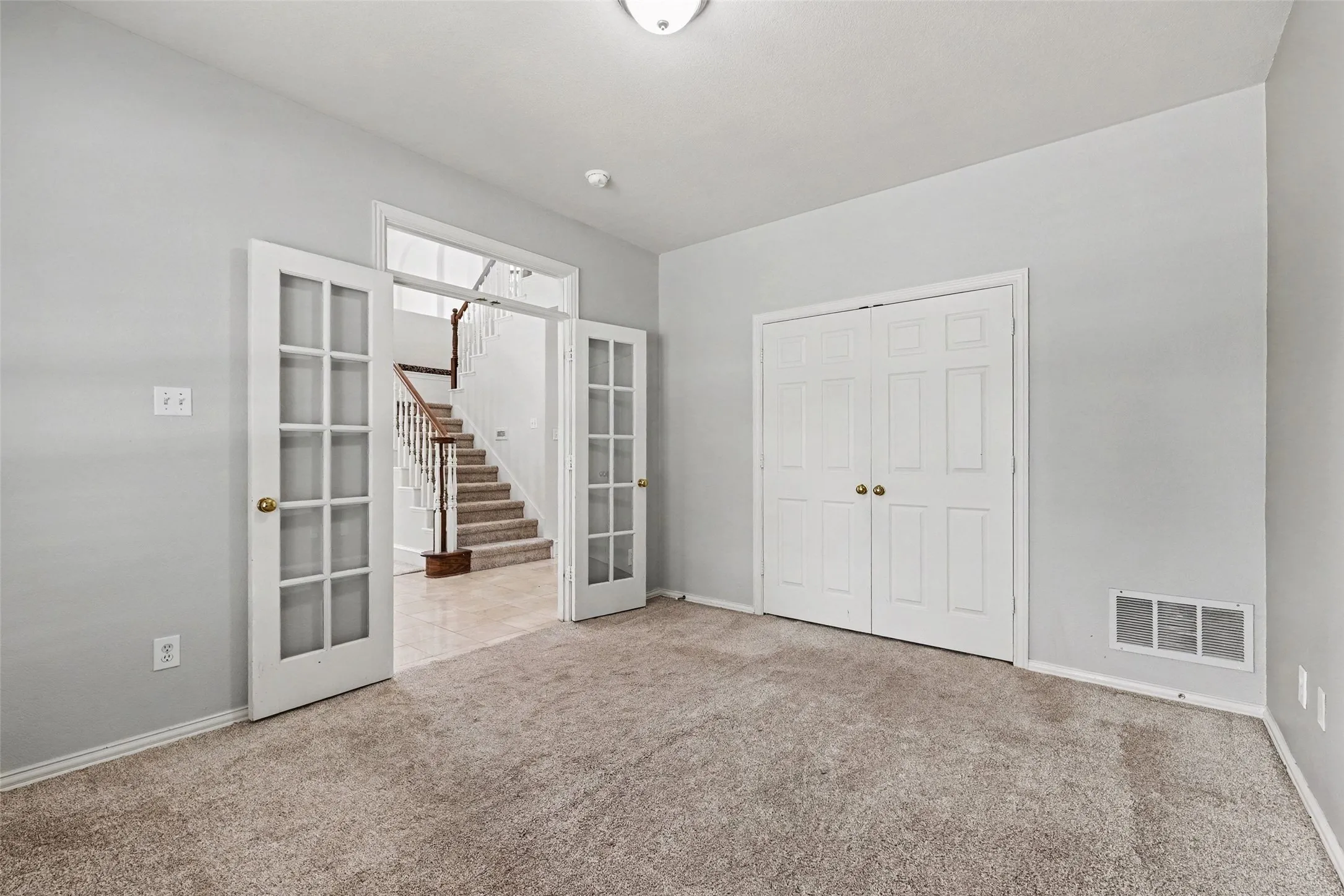 Carpeted room featuring French doors, a built-in closet, and a ceiling light fixture
