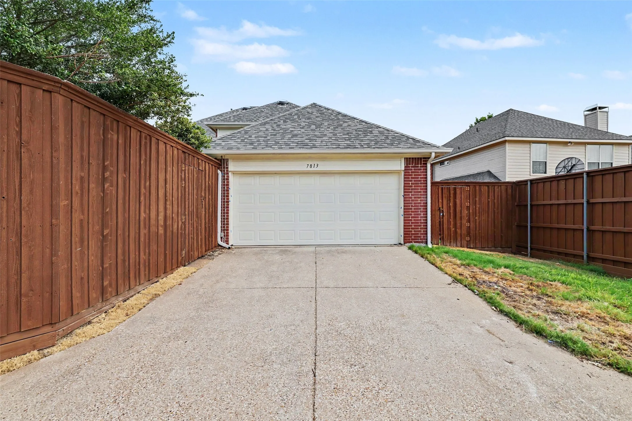 Spacious driveway with concrete surface leading to an attached two-car garage featuring a white sectional door