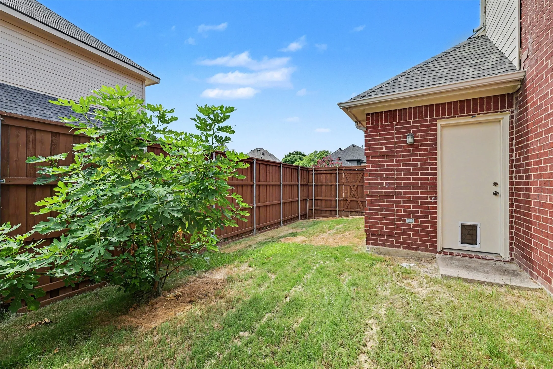 Brick exterior with a side entry door, enclosed by wood fencing
