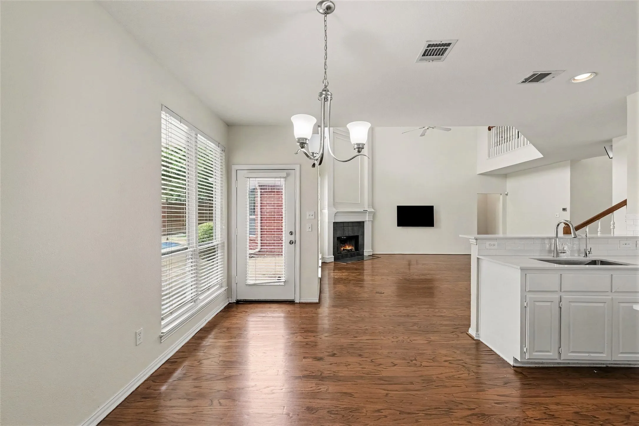 Wood-finish flooring, white cabinetry, integrated sink, and white subway tile backsplash