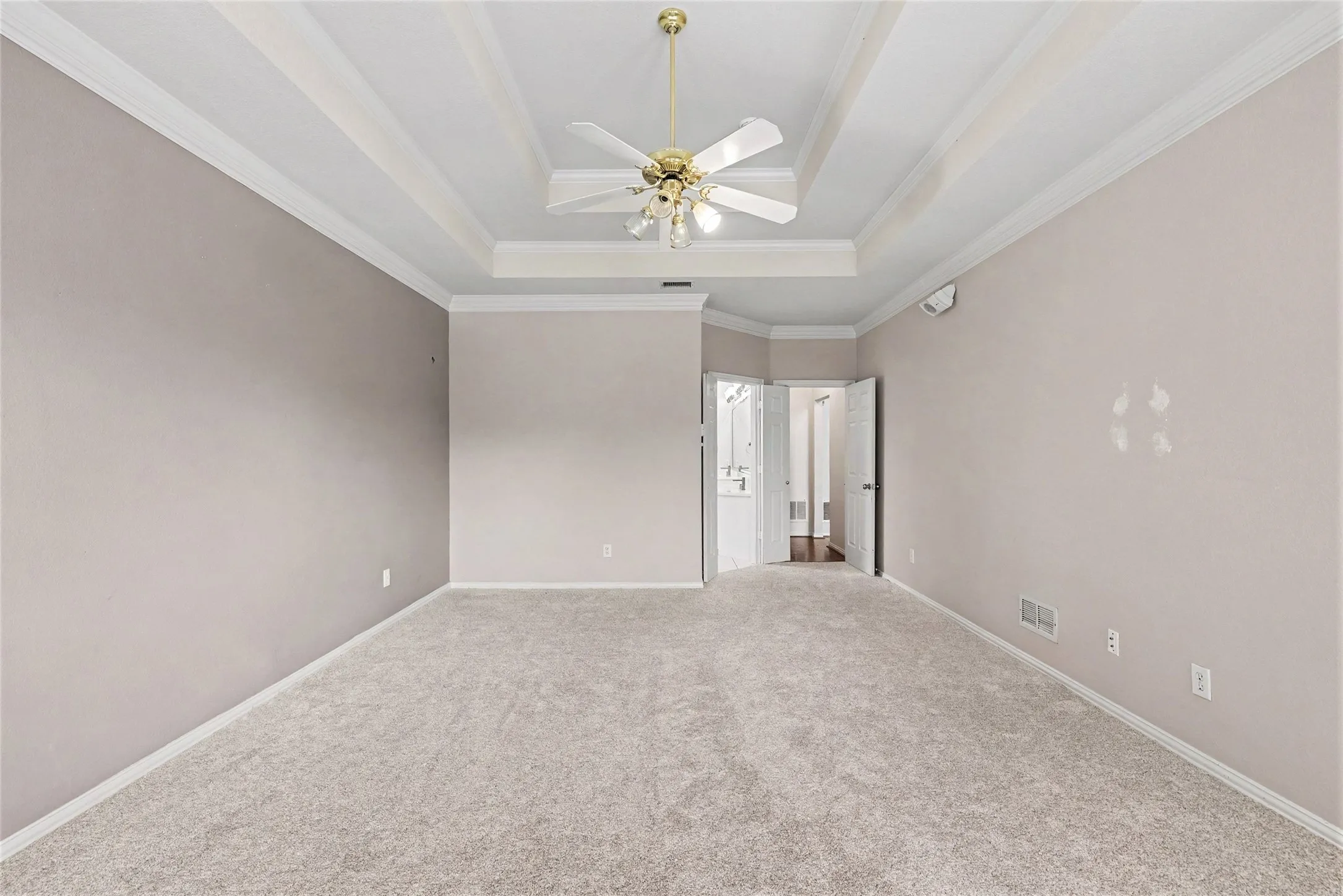 Tray ceiling with crown molding and a ceiling fan
