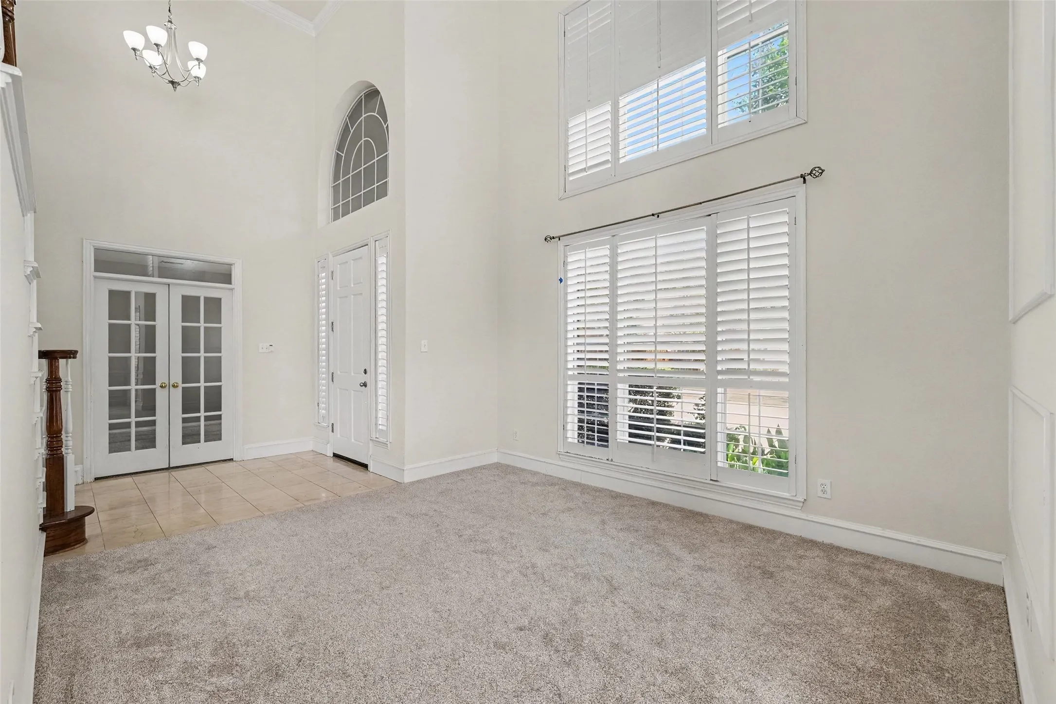 Two-story foyer featuring an arched transom window and chandelier