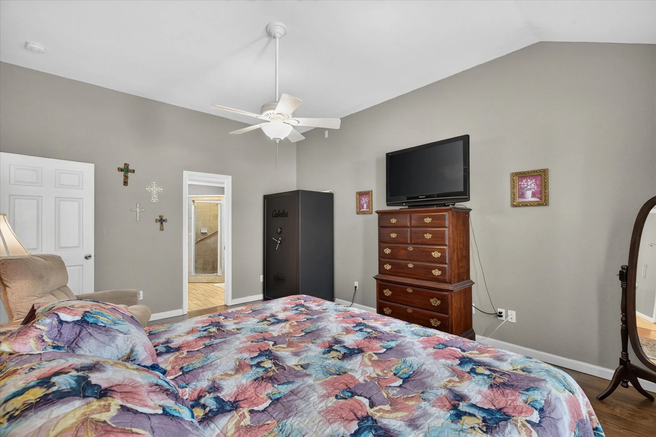 Vaulted ceiling featuring a centrally mounted white ceiling fan and wood-finish flooring