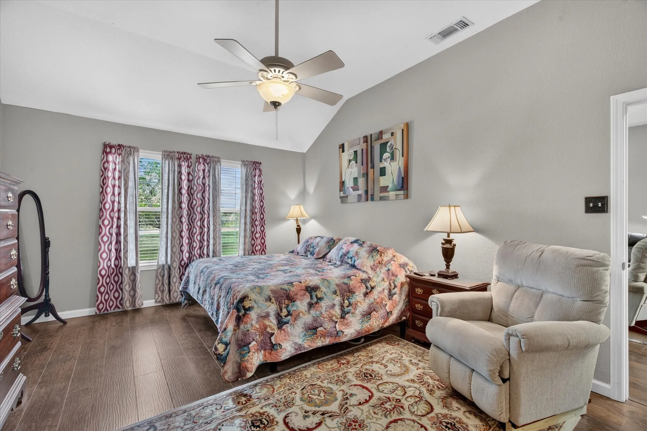Vaulted ceilings featuring a central ceiling fan with integrated lighting, wood-finish flooring, and expansive windows