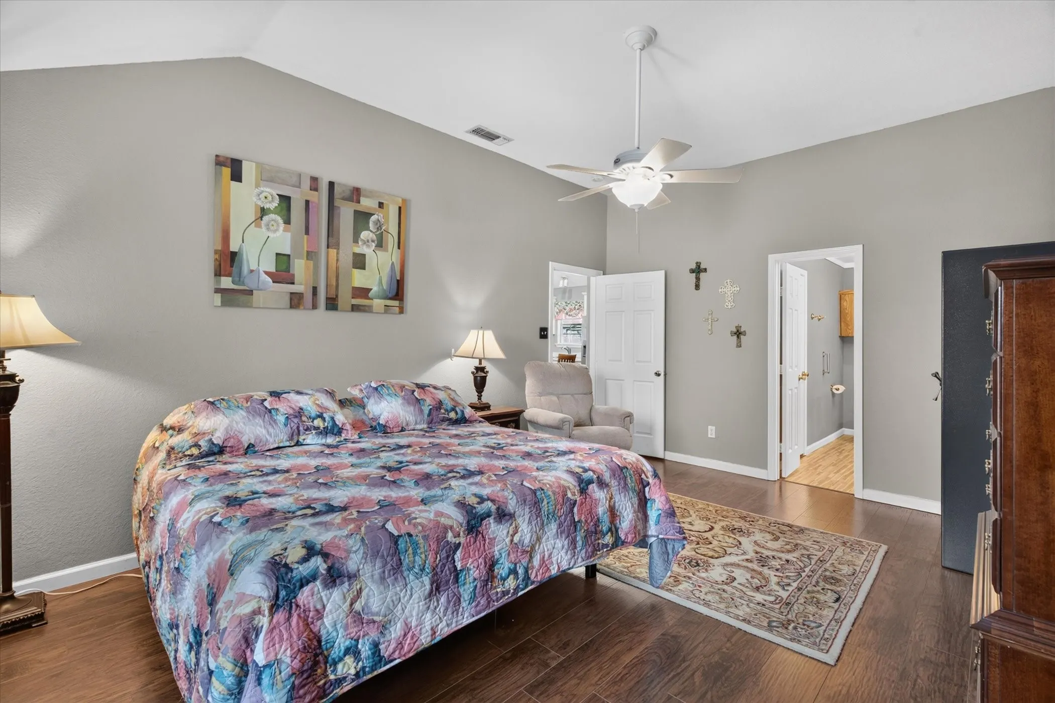 Vaulted ceiling with an integrated white ceiling fan and light fixture, wood-finish flooring, and multi-panel interior doors