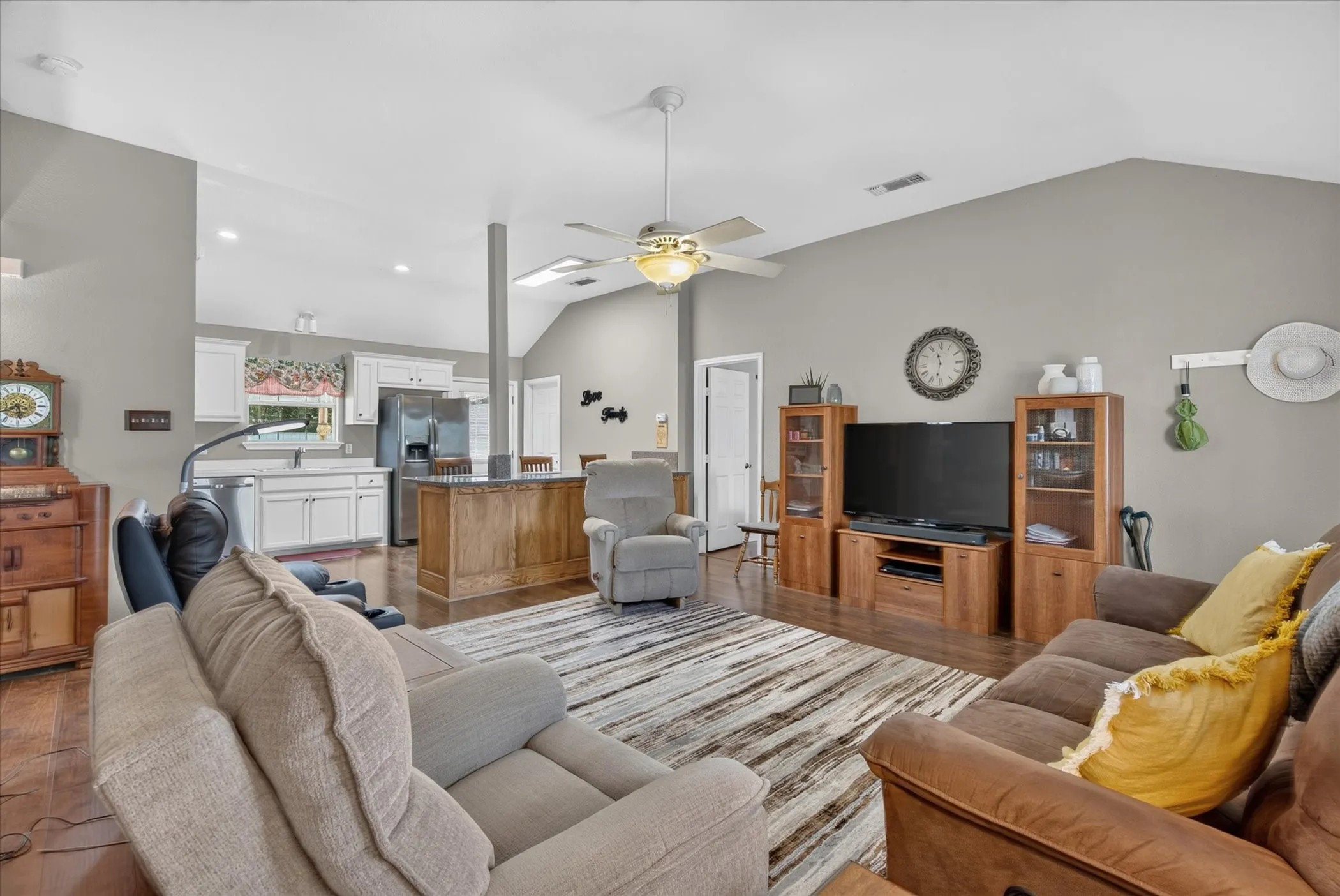 Vaulted ceilings, open-concept floor plan, central island with wood cabinetry, and recessed lighting