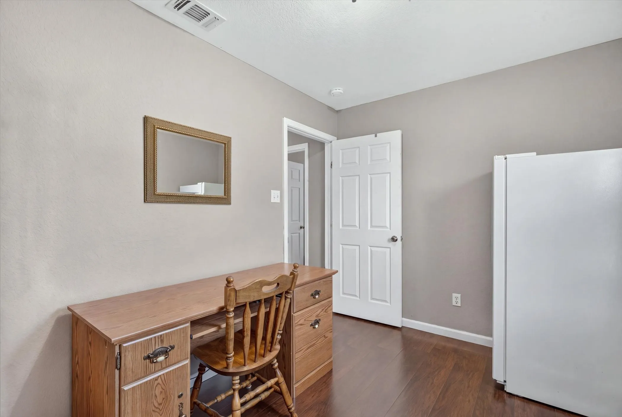 Neutral wall tones, wood-finish flooring, and a six-panel interior door