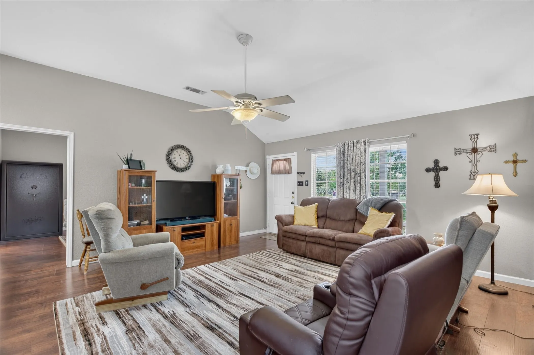 Living room featuring vaulted ceilings, wood-finish flooring, and a central ceiling fan with integrated lighting