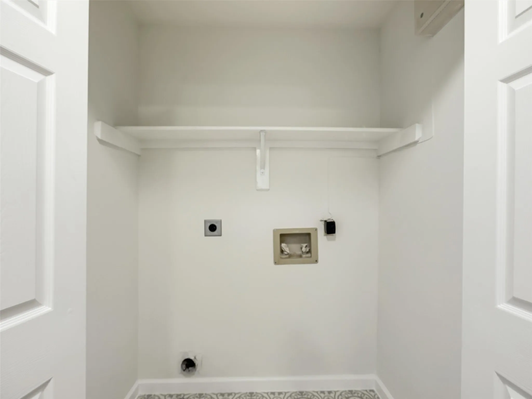 White wall paint, built-in shelving, patterned floor tile, and panel doors