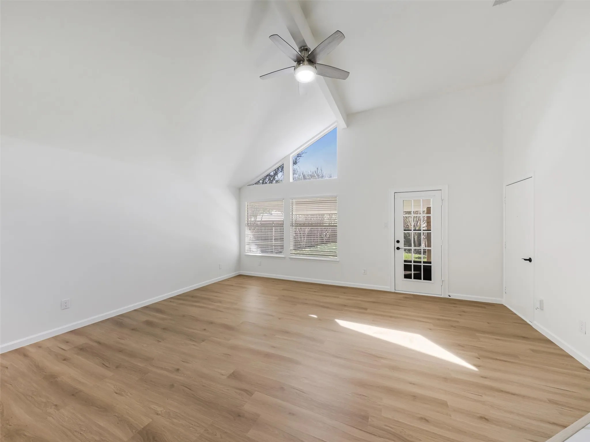 Vaulted ceiling, ceiling fan, wood-finish flooring, French door, and large windows