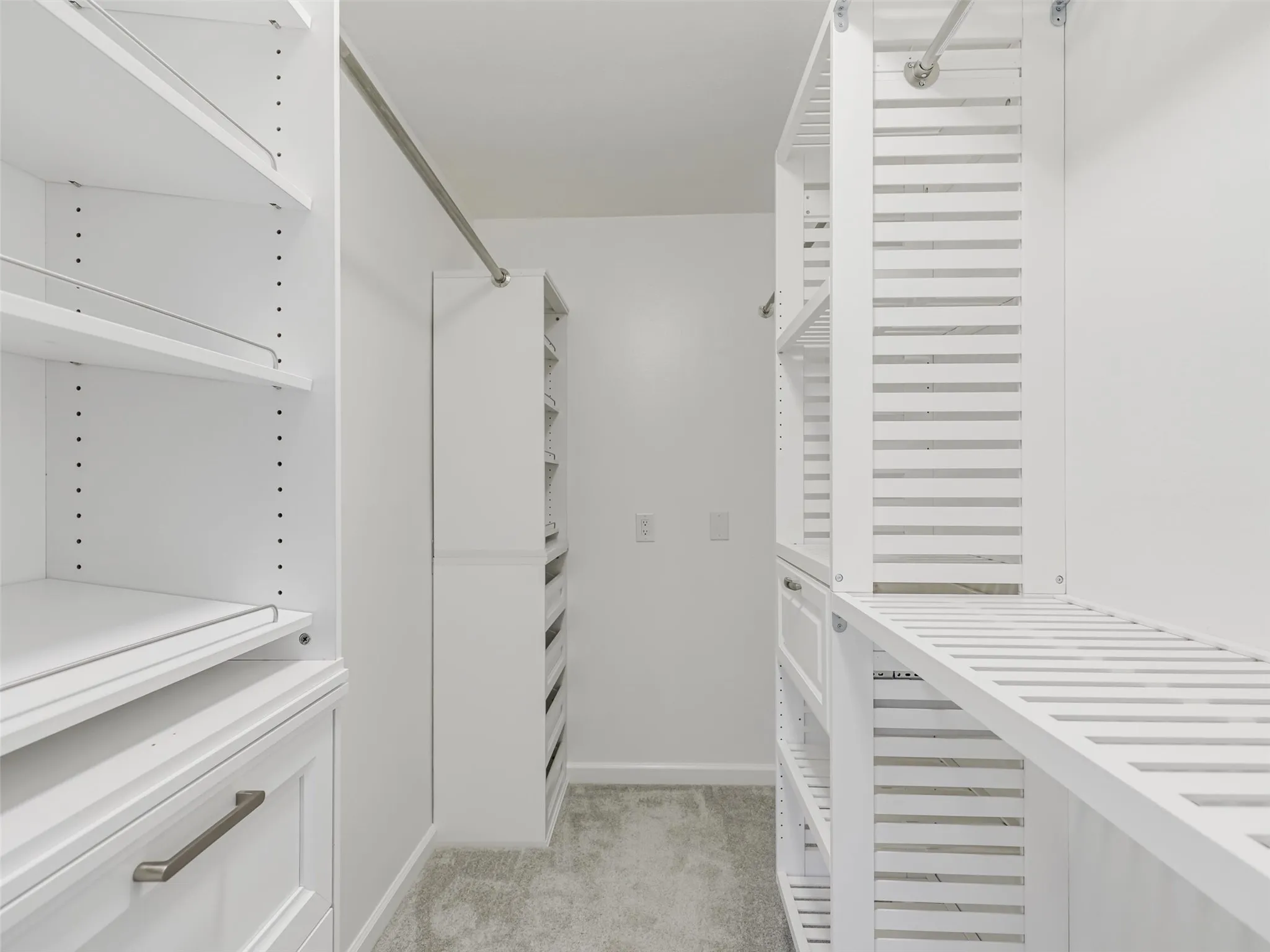Custom closet system featuring white shelving and drawers with brushed nickel hardware