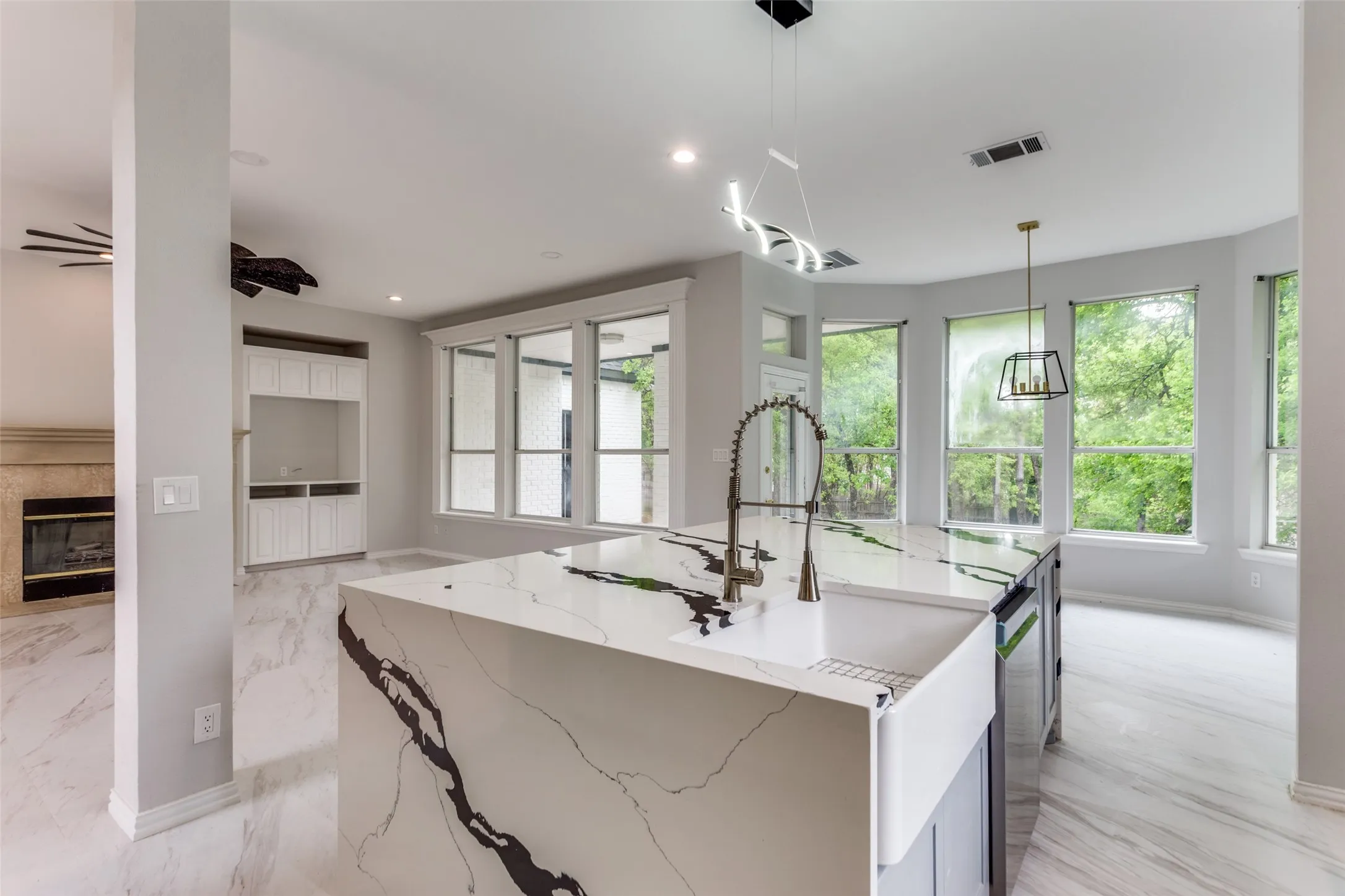 Kitchen island with a farmhouse sink and modern faucet, under a contemporary linear light fixture