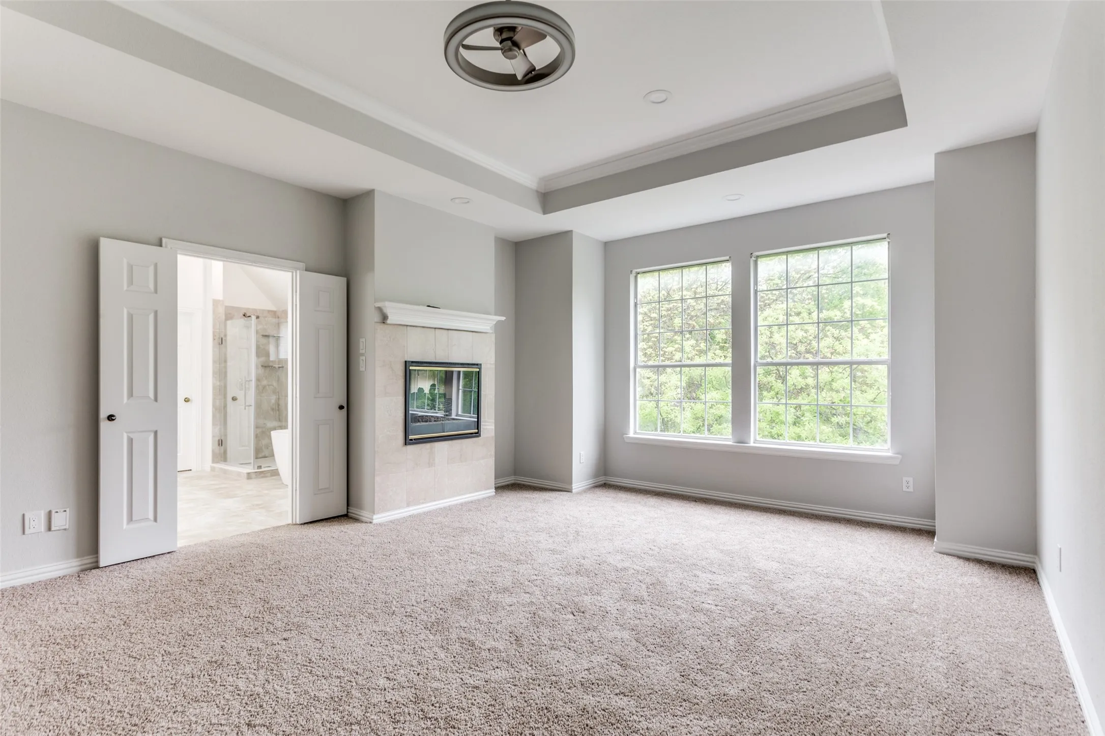 Recessed lighting, tray ceiling, ceiling fan, carpeted flooring, and a fireplace with a tiled surround