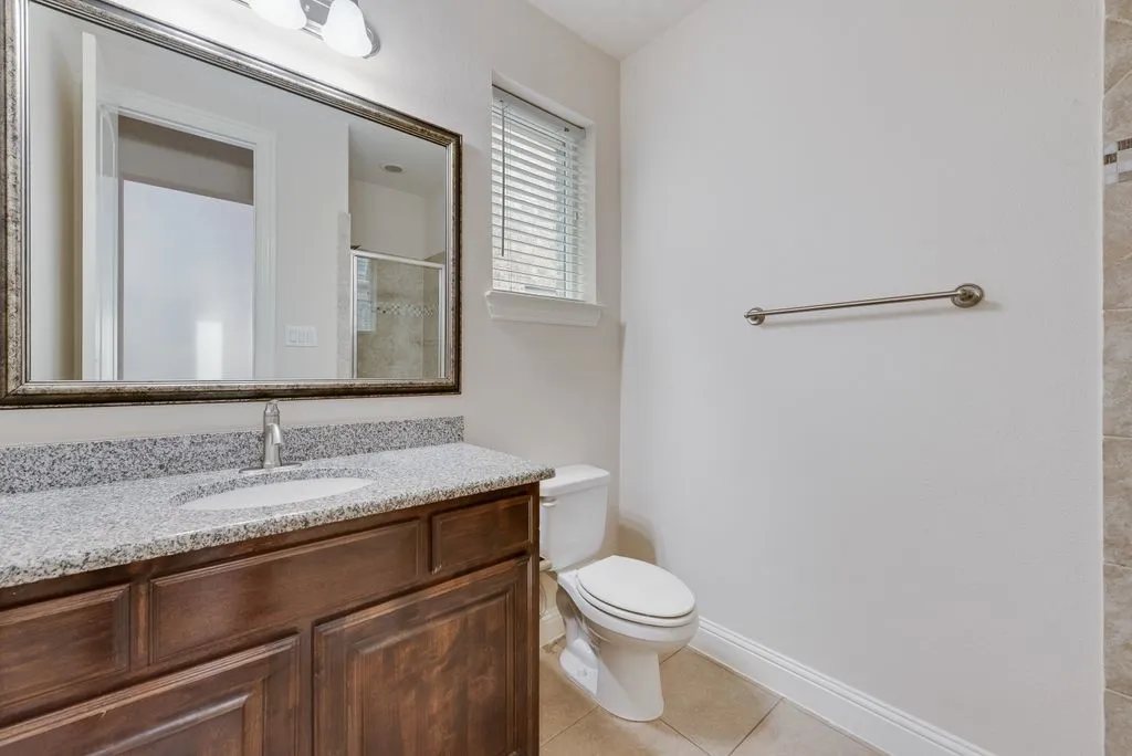 Bathroom vanity with a granite-style countertop, undermount sink, and wood-finish cabinetry