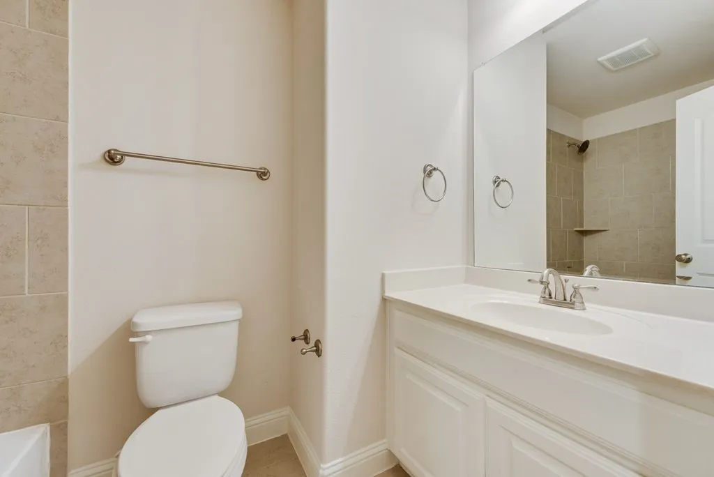 Bathroom featuring a vanity with an integrated sink, white cabinetry, and a large mirror