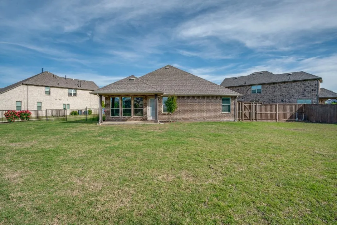 Expansive backyard featuring a brick exterior, covered patio, and large windows