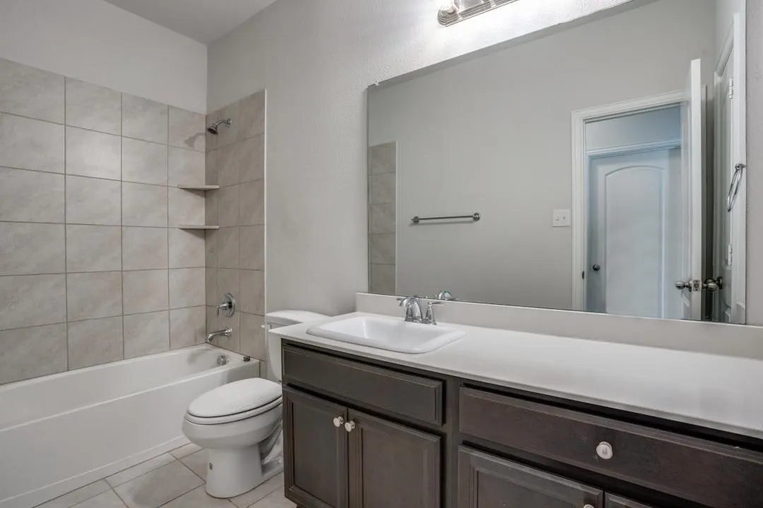 Vanity with a white countertop and integrated sink, chrome faucet, and dark wood-finish cabinetry