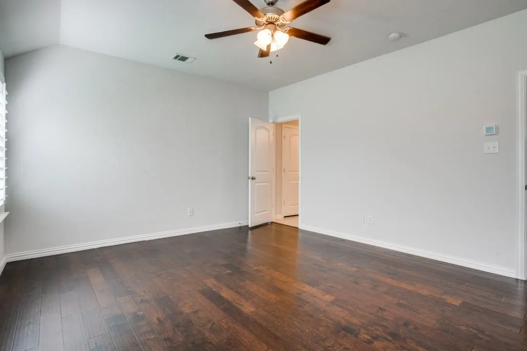 Vaulted ceiling, wood-finish flooring, ceiling fan, white interior doors, and window with blinds