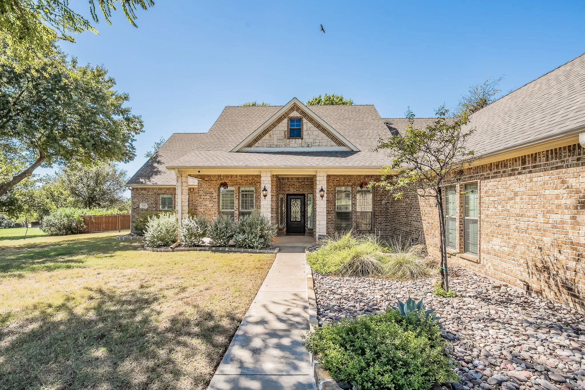 Brick exterior with stone accents, covered front porch, and gabled roofline